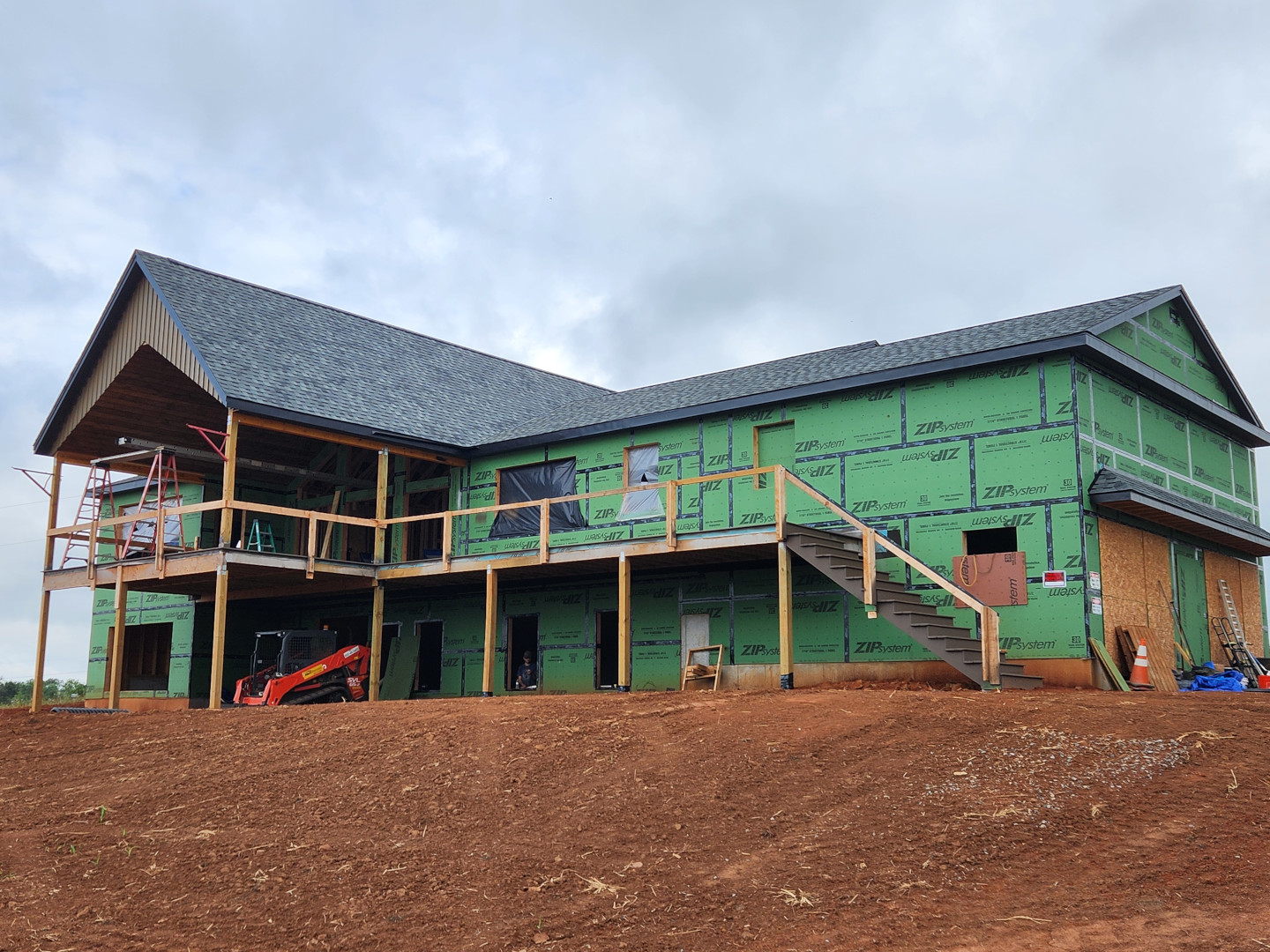 Limestone shot from driveway, showcasing finished roof, rear porch, and gable detail.